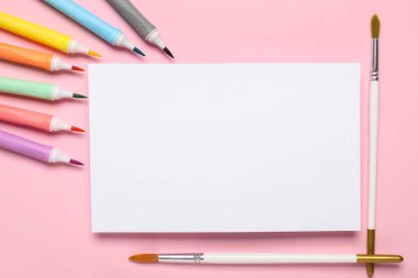 Keçeli kalemli kağıt yaprağı ve pembe arka planda boya fırçaları. Okul bitti. Üst görünüm