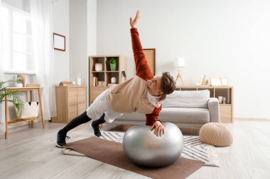 Sportif genç adam evde fitbol antrenmanı yapıyor.