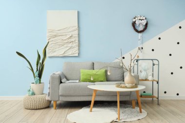 Kanepe, ağaç dalları ve Paskalya yumurtaları olan şık bir oturma odası.