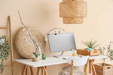 Ofiste bej duvarın yanında bilgisayar ve Paskalya dekoru olan bir işyeri