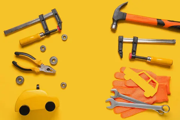 Set of mechanic tools, gloves and paper car on yellow background. Mechanic concept