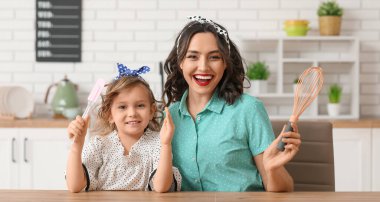 Güzel, mutlu bir kadın ve mutfakta mutfak aletleri olan kızı.