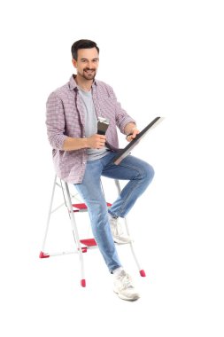 Beyaz arka planda oturan oyuncak bıçaklı genç bir adam.