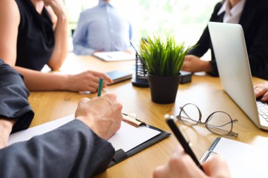 Toplantı salonundaki masada çalışan bir grup iş adamı, yakın plan.