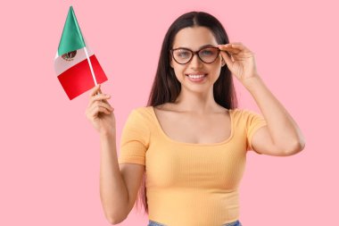 Pembe arka planda Meksika bayrağı olan genç bir kadın.