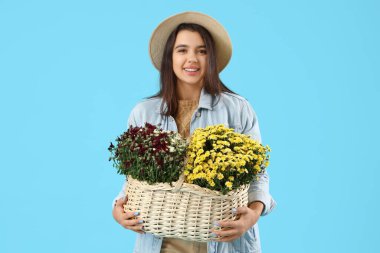 Mavi arka planda kasımpatı çiçekleri olan genç bir kadın.