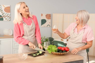 Olgun bayan arkadaşlar mutfakta salatalık kesiyor.