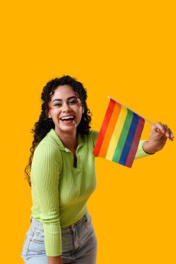 Sarı arka planda gökkuşağı bayrağı olan mutlu Afro-Amerikalı kadın. LGBT kavramı
