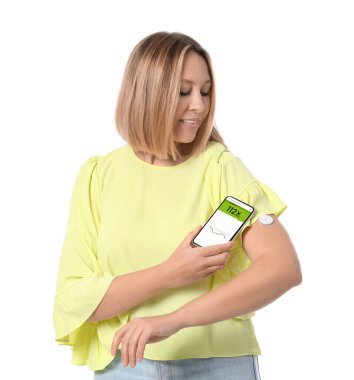 Glikoz sensörü olan diyabetik bir kadın beyaz arka plandaki kan şekerini ölçmek için cep telefonu kullanıyor.