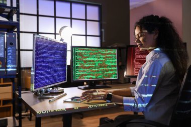 Kadın Afro-Amerikalı programcı gece ofiste bilgisayarla çalışıyor.