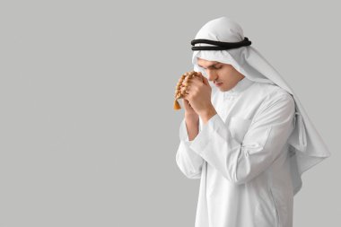 Genç Müslüman bir adam tasbih ile arka planda namaz kılıyor