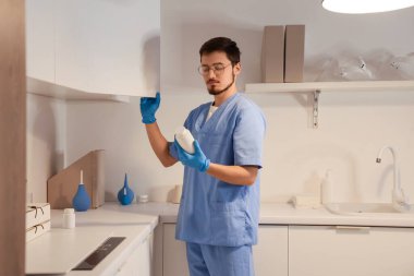 İlaç şişesi olan erkek hemşire klinikte gece vardiyasında çalışıyor.