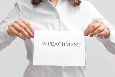 Beyaz arka planda IMPEACHMENT pankart posteri tutan kadın