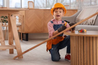 Şirin küçük inşaatçı odada tahta çivi çakıyor.