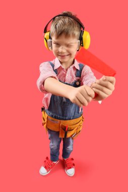 Kırmızı arka planda cetveli olan şirin bir inşaatçı.