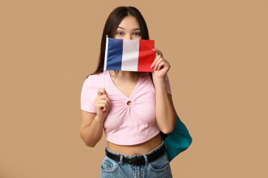 Bej arka planda Fransız bayrağı olan bir kız öğrenci.