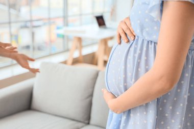 Genç hamile kadın klinikte doktoru ziyaret ediyor, yakın plan.