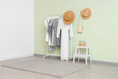 Beyaz duvarın yanında modaya uygun kıyafetler ve şapkalar.