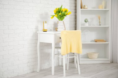 Yatak odasındaki tuvalet masasındaki sarı lalelerin güzel vazosu.