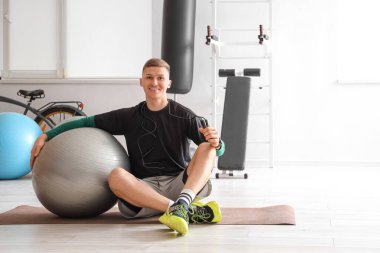 Spor salonunda ip atlayan ve fitbol oynayan genç bir adam.