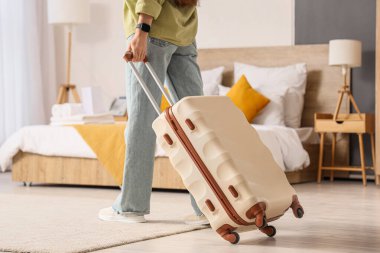 Otel odasında bavullu bir kadın turist yürüyor.