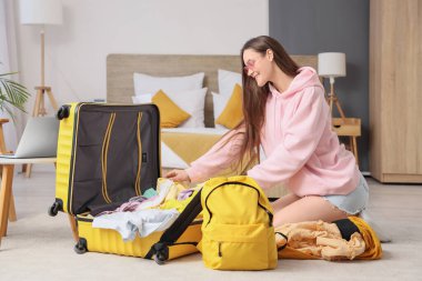 Otel odasında bavul dolusu elbisesi olan bir kadın turist.