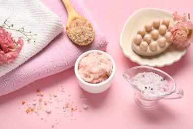 Pembe arka planda vücut fırçası, deniz tuzu ve temiz havlular.