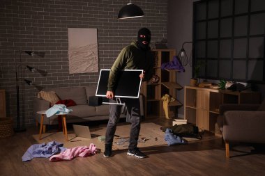 Erkek hırsız gece odada monitör çalıyor.