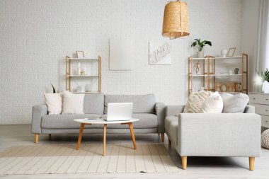 Masada dizüstü bilgisayar ve kanepelerle aydınlık oturma odasının içinde.