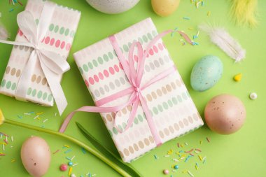 Paskalya hediyeleri ve yeşil arka planda boyanmış yumurtalar.