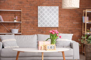 Çiçekli vazo, hediye kutusu ve takvim oturma odasındaki sehpanın üzerinde.