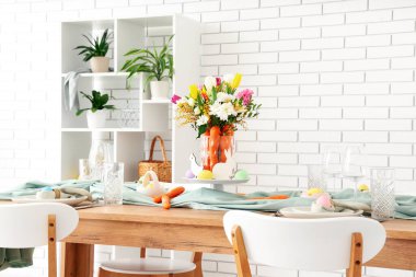 Paskalya için çok güzel bir masa. Beyaz tuğla duvarın yanında havuç ve çiçeklerle süslenmiş.