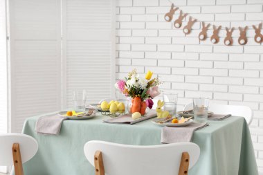 Paskalya için çok güzel bir masa. Beyaz tuğla duvarın yanında havuç ve çiçeklerle süslenmiş.