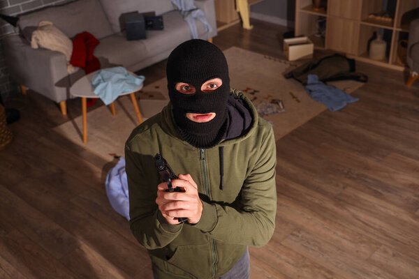 Мужчина-вор с пистолетом в комнате ночью