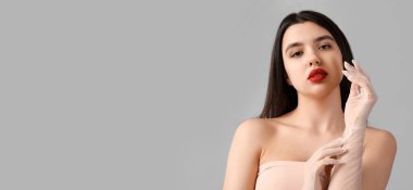 Gri arkaplan üzerinde kırmızı dudakları olan güzel genç bir kadın.