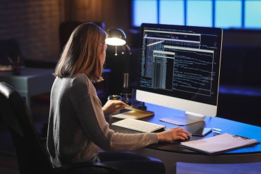 Geceleri bilgisayarla çalışan kadın programcı.
