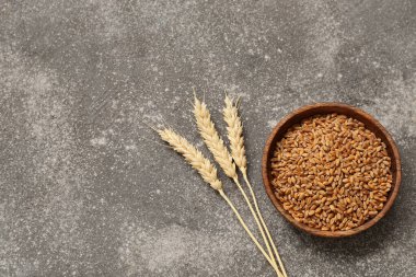 Buğday kulaklı ahşap kase ve grunge masasında tahıllar.