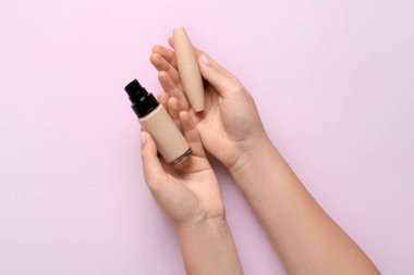 Sıvı makyaj temeli olan kadın elleri ve renk arkaplanda göz kalemi, yakın plan