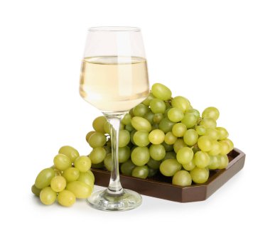 Tahta tahta, üzümler ve beyaz arka planda bir bardak nefis şarap.