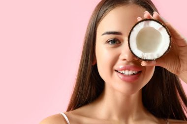 Pembe arka planda hindistan cevizi olan güzel genç kadın, yakın plan.