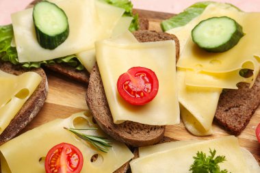 Peynirli, salatalıklı ve domatesli lezzetli sandviçler masada, yakın plan.