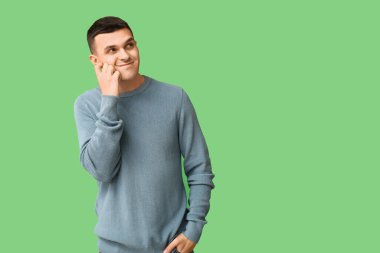 Yeşil arka plandaki yakışıklı, utangaç genç adam.