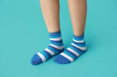 Mavi arka planda çizgili çoraplı genç kadın bacakları