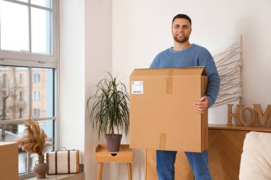 Evinde büyük bir paket kutusu olan genç bir adam.