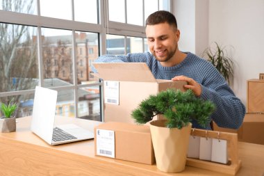 Evdeki masada paketleri açan genç adam.