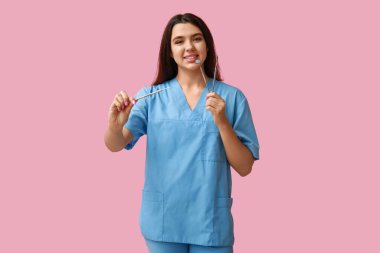 Pembe arka planda aletleri olan kadın dişçi. Dünya Diş Hekimi Günü