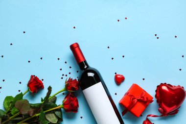Güllü bir şişe şarap, mavi arka planda hediye ve dekor. Sevgililer Günü kutlaması