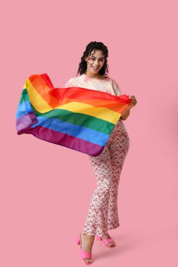 Pembe arka planda gökkuşağı bayrağı olan genç bir Afro-Amerikalı kadın. LGBT kavramı