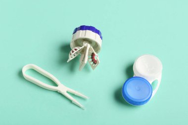 Konteynır ve cımbızla turkuaz arka planda kontak lensler için temizlik çantası