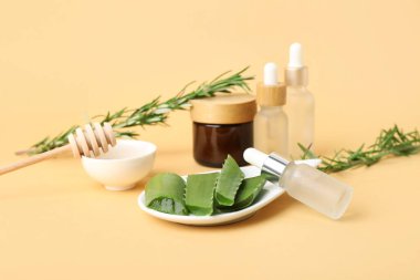 Kozmetik ürünler seti, aloe vera yaprakları, biberiye ve bal renkli bal çubuğu
